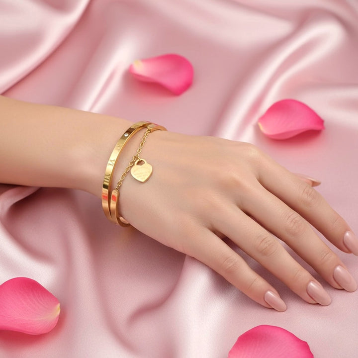 Gold bracelet on a hand with pink petals on a pink satin background